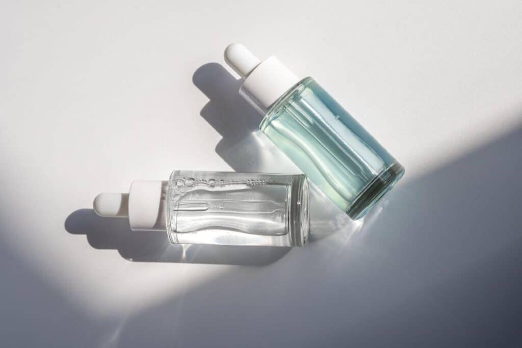 Two glass dropper bottles with skincare serums on a white background, promoting anti-aging cosmetic.