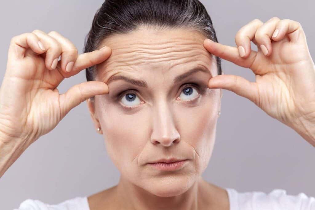 Woman demonstrating anti-aging facial procedures in Albania for youthful skin.