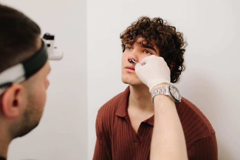 Le médecin examine un jeune homme pour une procédure de rhinoplastie en Albanie.