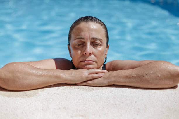 Vrouw ontspannend bij het zwembad, met nadruk op relaxatie en welzijn.