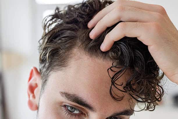 Junger Mann mit gesundem, gestyltem Haar, der Behandlungen für Haarpflege in Albanien bewirbt.