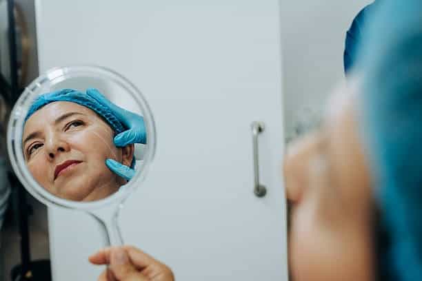 Femme subissant une chirurgie esthétique se reflétant dans un miroir dans une clinique médicale albanaise.