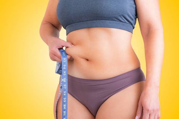 Woman measuring her waist for weight loss or body fitness.