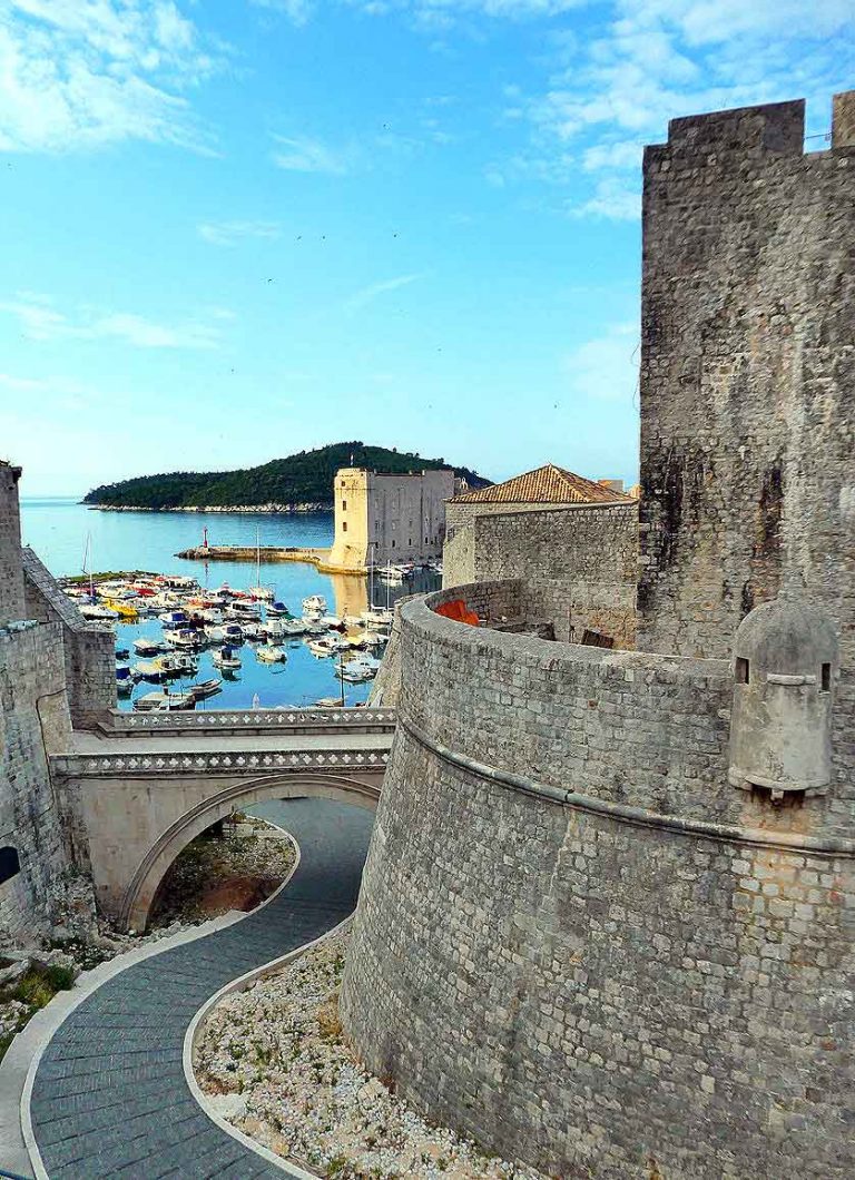 Early morning sunlight outside of Dubrovnik City Walls looking throuhg an archway at the harbour. A complete guide to visiting Dubrovnik in 2 days. Included in this Dubrovnik 2 days itinerary are the top things to see in Dubrovnik. Learn everything about how to visit Dubrovnik in two days with this complete 2 days in Dubrovnik itinerary guide.