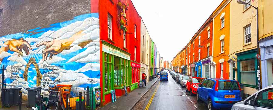 Vibrant colourful houses and murals along Picton Street with cars parked on the side of the street