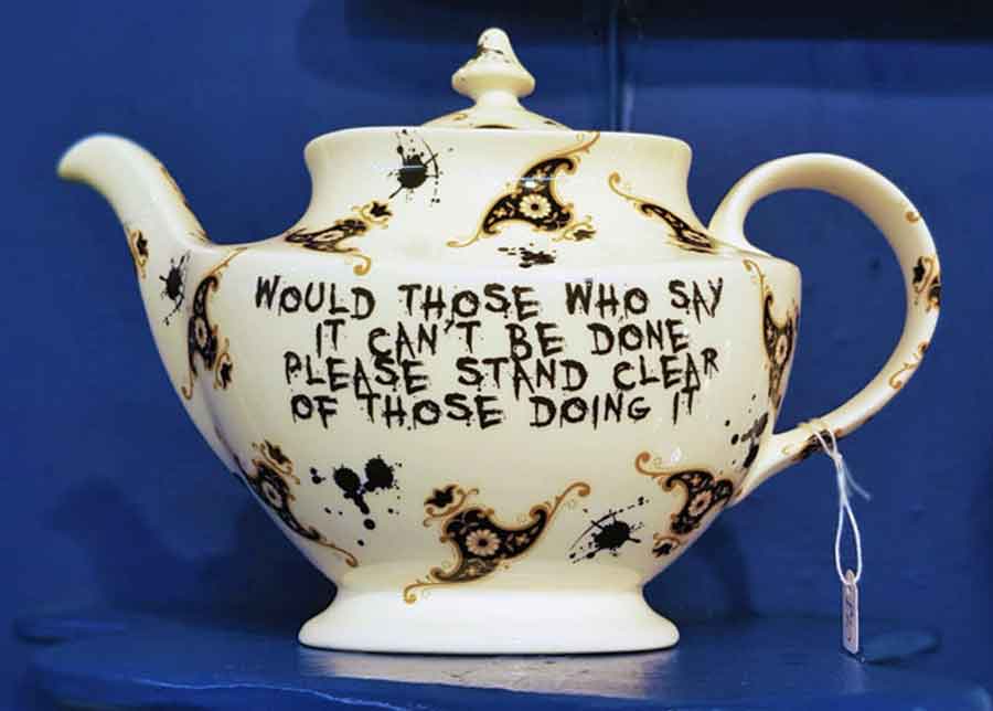 A tea pot with paint quotes saying "Would those who say it can't be done please stand clear of those doing it"