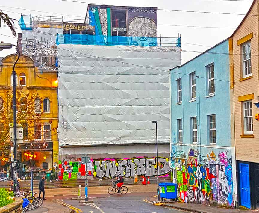 Westmoreland House clad with scaffolding and street art scenes painted on different walls  of the building