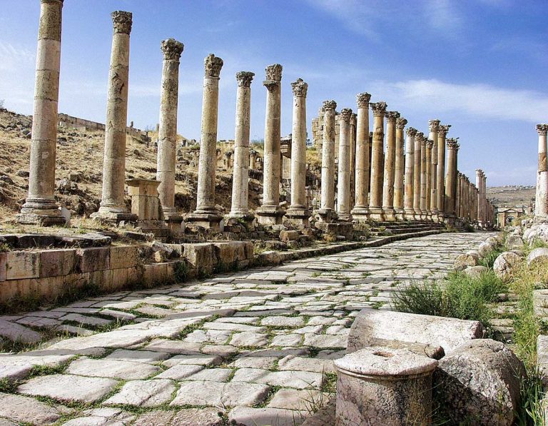 Cardo Maximus in Jerash, Jordan, showcasing its multiple tall old columns lined in a row with an old brick stone pathway under a clear blue sky