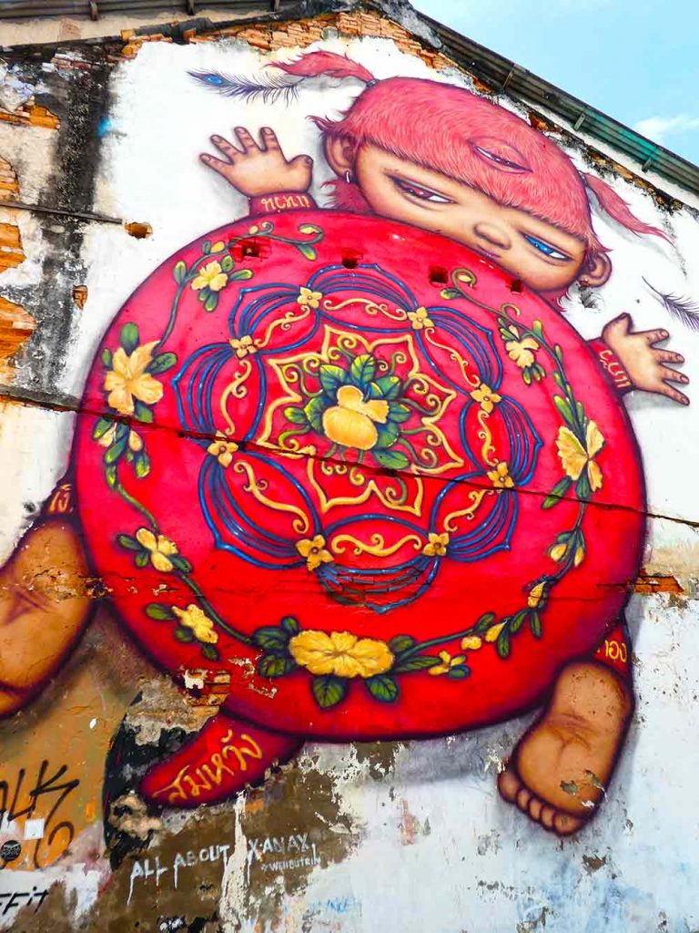The 'Red Turtle Cake' mural by Alex Face can be found at the junction of Romanee Road and Thalang Road.