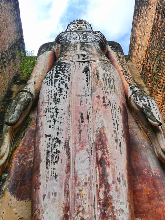 Giand Buddha standing at Sukhotai Ruins, Thailand in a clear blue sky