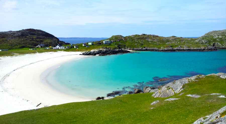 33 Best Hidden Coves and Secluded Beaches Around the World 18 Achmelvich Cove in Scotland features a white sand and bllue water at the center surrounded by green islands on a clear blue sky