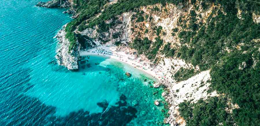 33 Best Hidden Coves and Secluded Beaches Around the World 28 An aerial view of Agiofili Beach in Greece with its turquiose clear water and mountains covered with trees