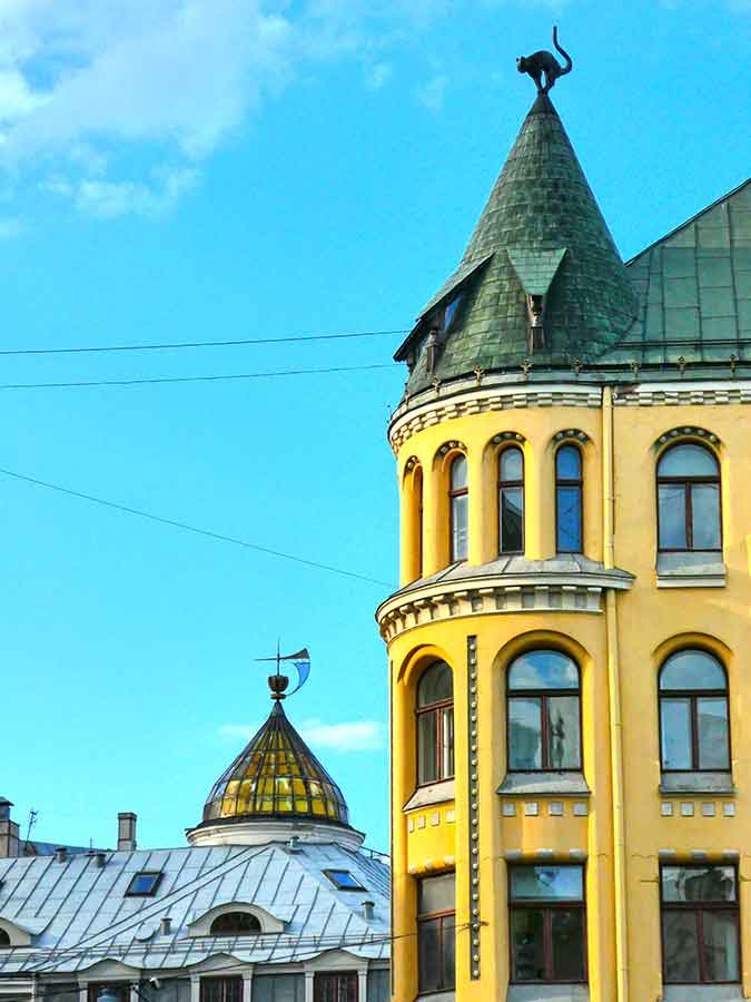 Best Riga 3 Days Itinerary: Exploring ‘Paris of the North’ 11 Building in Riga with yellow walls and windows. The building has a round tower and on the top is a cat in bronze on the roof.