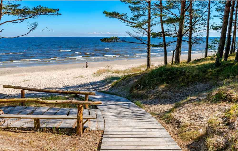 Best Riga 3 Days Itinerary: Exploring ‘Paris of the North’ 28 A board walk leading down to Jurmala Beach. There is white sand and someone walking their dog on the beach.