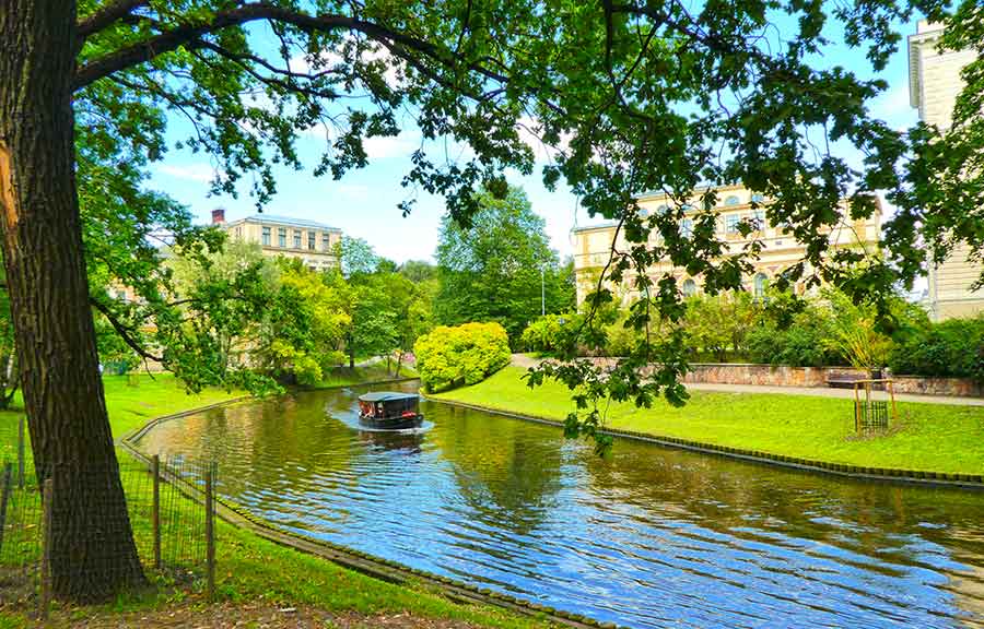 Best Riga 3 Days Itinerary: Exploring ‘Paris of the North’ 27 A canal running through a park in Riga with a boat on it.