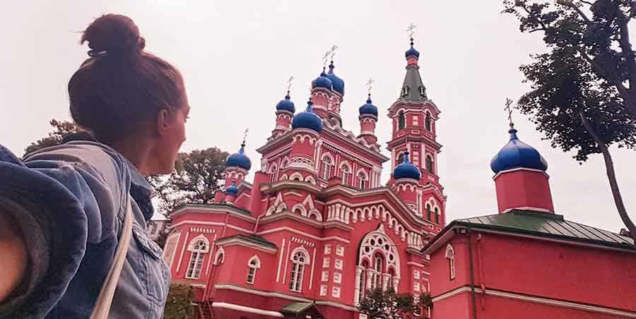 Best Riga 3 Days Itinerary: Exploring ‘Paris of the North’ 18 A woman (me) looking up at the pink church of Holy Trinity Church in Riga.