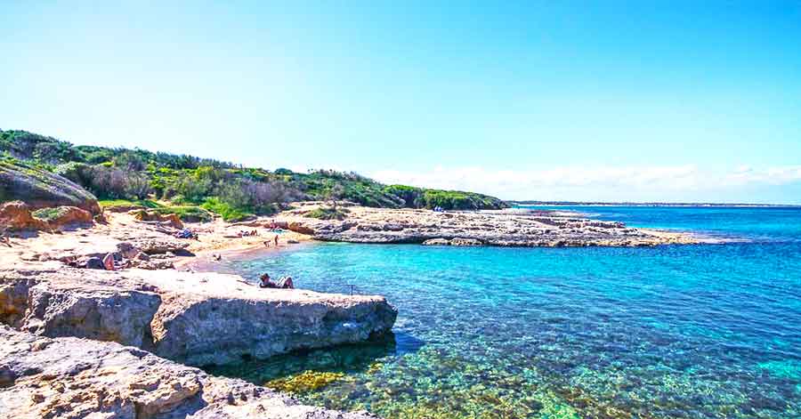 33 Best Hidden Coves and Secluded Beaches Around the World 21 Caletta Toraiello located in Italy showcasing its clear blue water with rocks at the shoreline on a clear blue sky