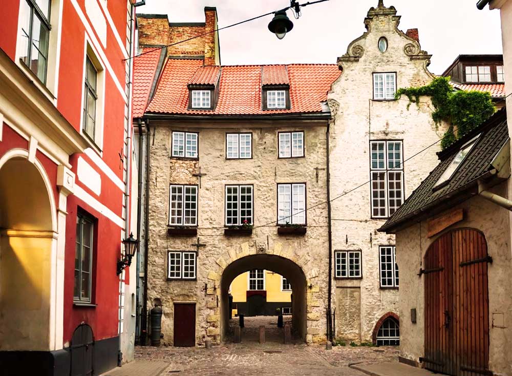 Best Riga 3 Days Itinerary: Exploring ‘Paris of the North’ 16 An old archway called the Swedish Gate featues a tunnel going through a pal stone buildings.