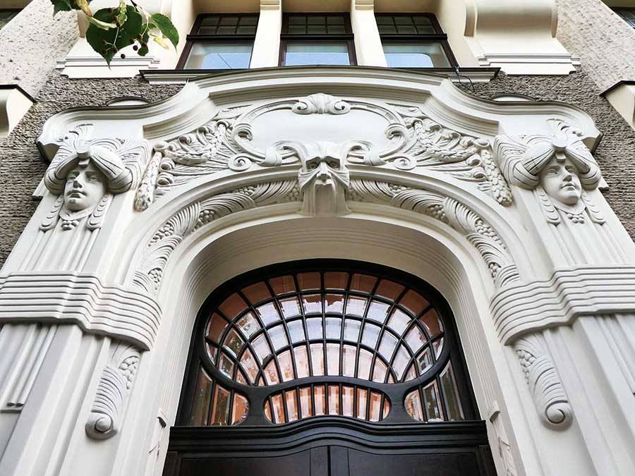 Where to See Art Nouveau in Riga, Latvia: Exploring The Art Nouveau District, Riga 1 Entrance of the Apartment Building at Elizabetes Street 23 adorned with carved faces and intricate details at the top of the arch entrance
