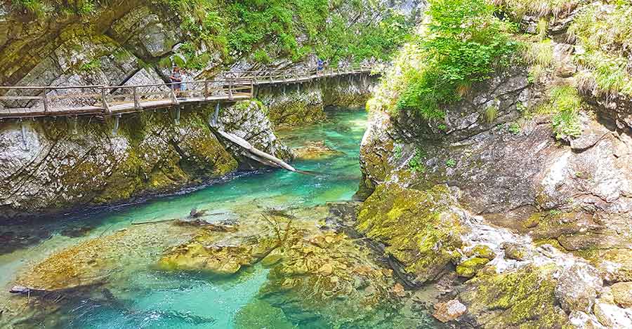 Vintgar Gorge showcasing strikingly clear and emerald green waters flanked by towering limestone cliffs that rise on both sides