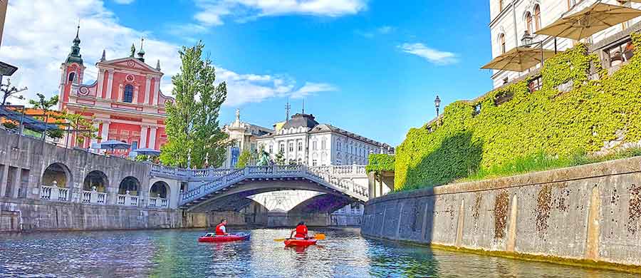 The Pink Franciscan Church and a bridge over the Ljubljanica River during sunny day