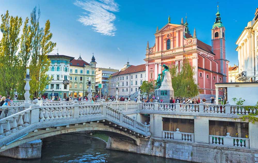 Preseren Square, the pink Franciscan church, vibrant buildings, and the triple bridge on a sunny day