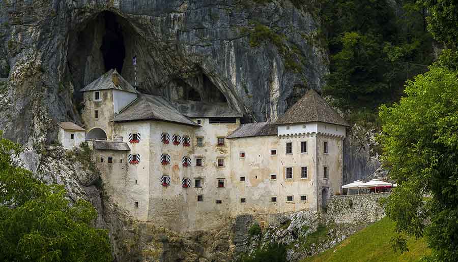 Predjama Castle perched into the cliffside of a towering rock wall
