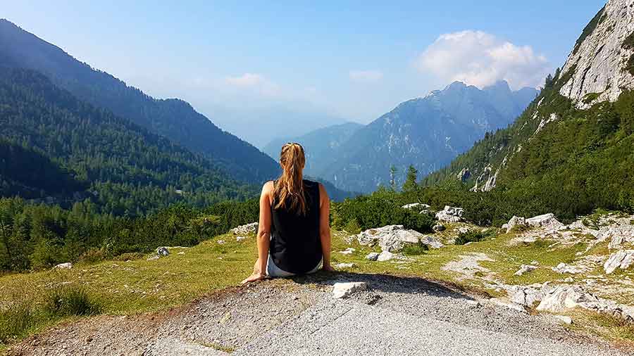 A woman sitting at the corner of the stone admiring the stunnning view of the Vrsic Pass, Slovenia
