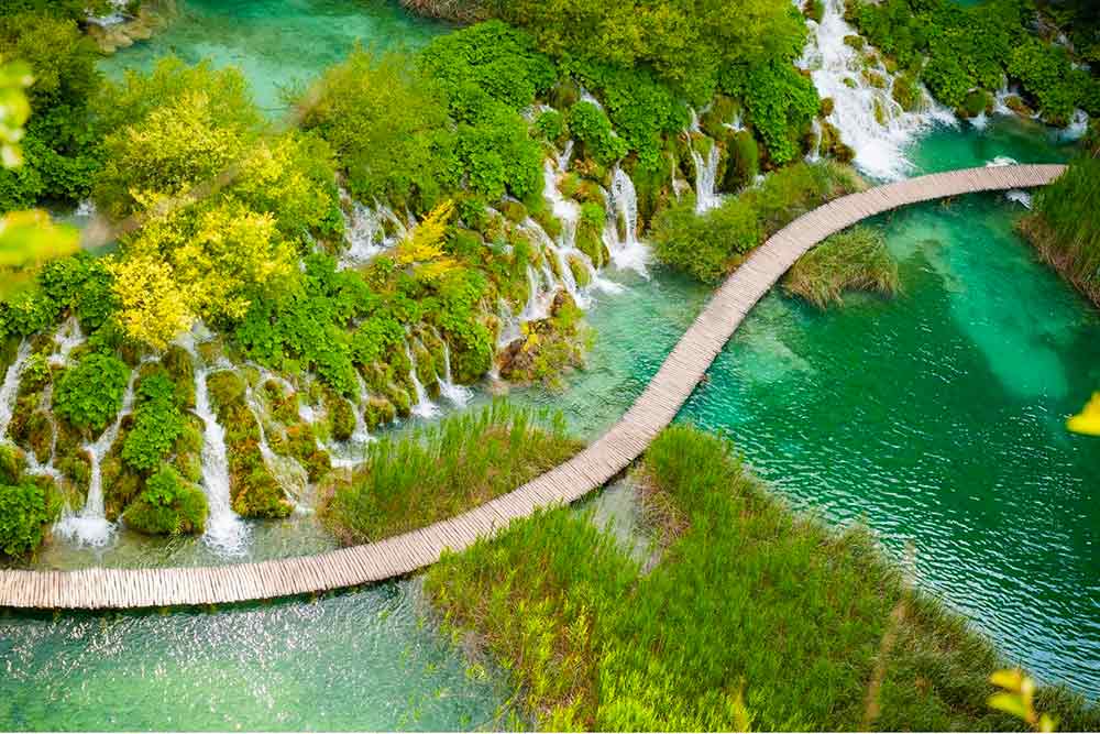 view of plitvice lakes from above, looking down on waterfalls and the boardward at the UNESCO listed site in Croatia. You can visit the lakes on a day trip from Dubrovnik