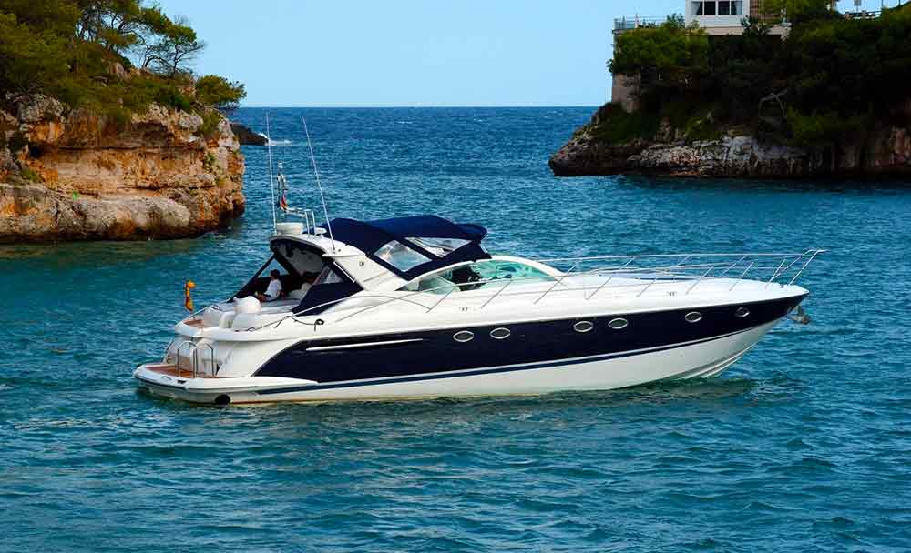 Speed boat in the ocean between two islands. The sea and sky are blue.