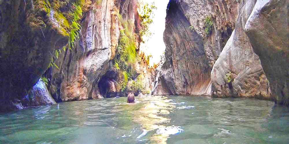 Extreme Adventures in Europe: 29 Best Adventure Sports in Europe 29 A woman is swimming in Guadalmina river in Spain, surrounded by high cliffs, creating a stunning natural setting