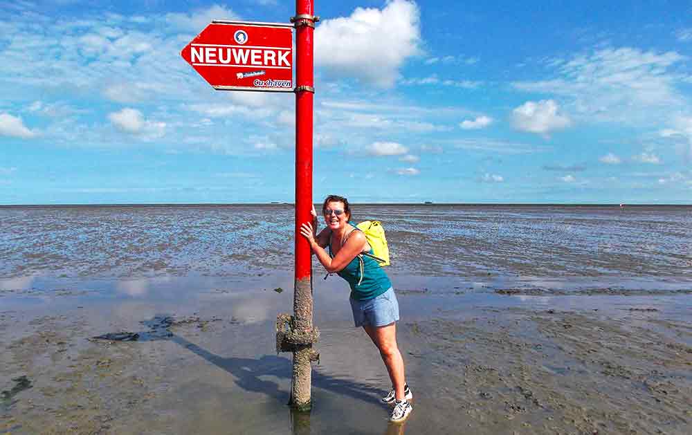 Extreme Adventures in Europe: 29 Best Adventure Sports in Europe 12 A woman is standing in squishy mud against a red signpost