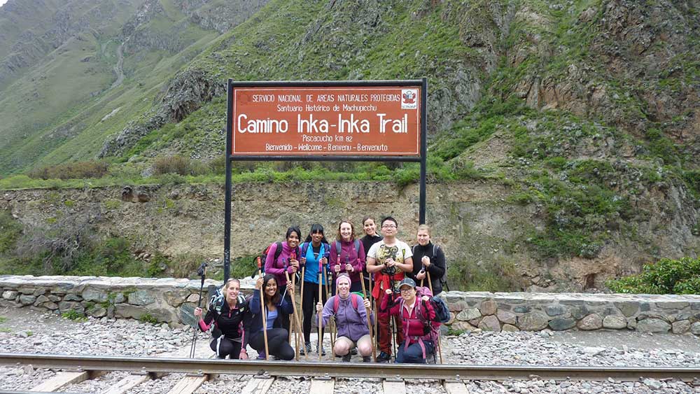 G Adventures Inca Trail Review: What to Expect on The Inca Trail Trek to Machu Picchu 5 Our group of 10 people standing in front of the sign at the start of the inca trail - we are carrying backpacks and holding walking poles