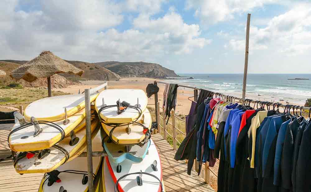 Extreme Adventures in Europe: 29 Best Adventure Sports in Europe 18 Surfboards and swimsuits are displayed at the shoreline of the beach, inviting beachgoers to enjoy the water and the sun