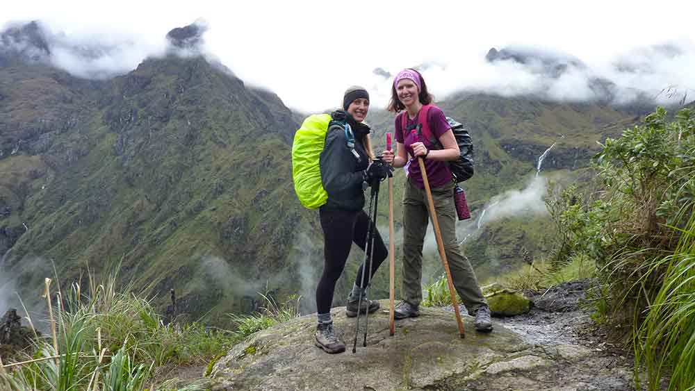 G Adventures Inca Trail Review: What to Expect on The Inca Trail Trek to Machu Picchu 17 Two women (one is me) stood with out hiking poles in front of the mountains. The weather is grey and there are low clouds on the mountain as we go up the Dead Womans Pass part of the Inca Trail.