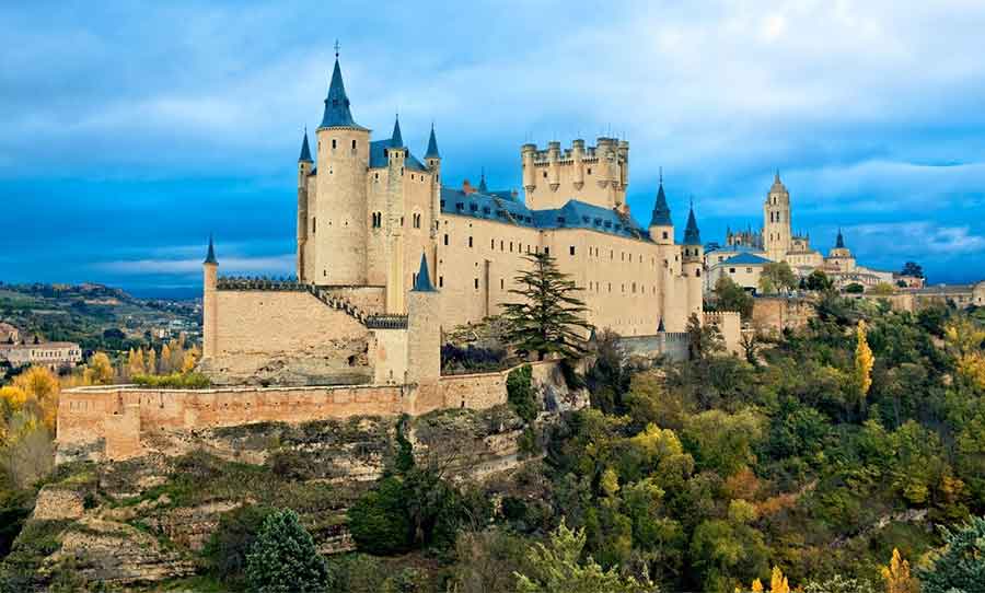 The Alcázar of Segovia perched above the forested valley, a fairy tale–like fortress and one of Spain’s most recognisable castles.
