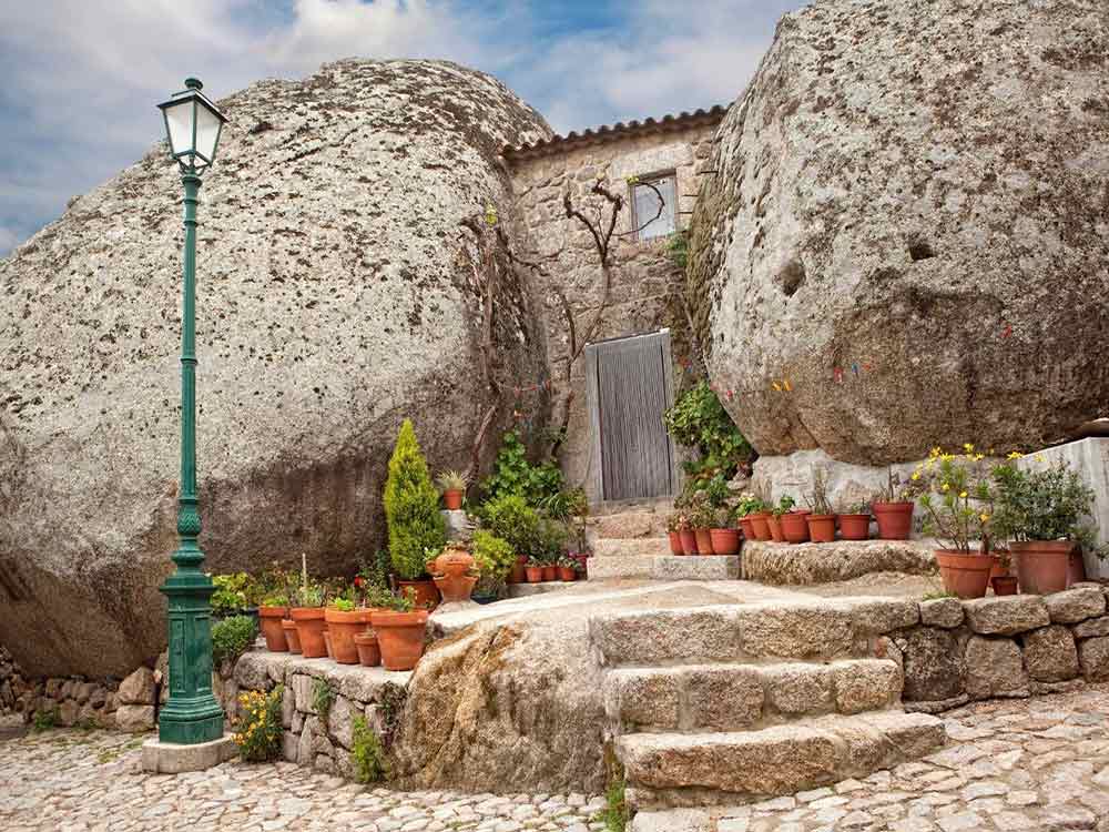 Monsanto Village featuring a house sandwiched between gigantic spherical-shaped large rock with potted plants at the entrance