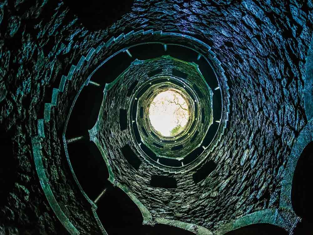 The Initiation Well in Quinta da Regaleira features a round well adorned with elaborate stonework.