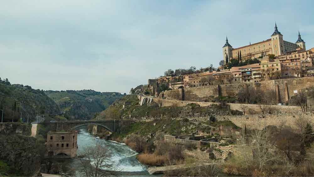 Madrid In Winter: Over 30 Things to Do In Winter in Madrid 4 The medievel city of Toledo In Winter perched on a hill with bare trees and grey sky