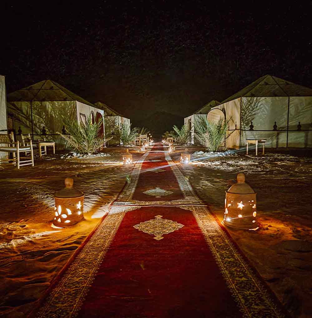 Rugs laid out at the camp with lanterns and ambient lighting at the camp at night.