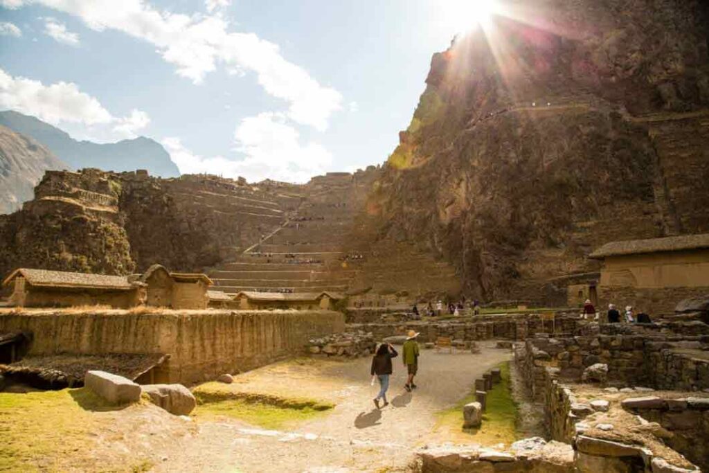 Ollantaytambo Ruins with people exploring the site sat on a mountainside. 