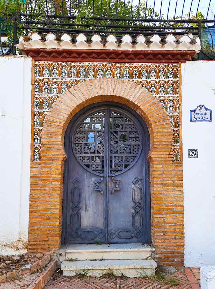 The doorway in the Albaicín District showcase their beauty with pattern mosaic at the entrance with black door