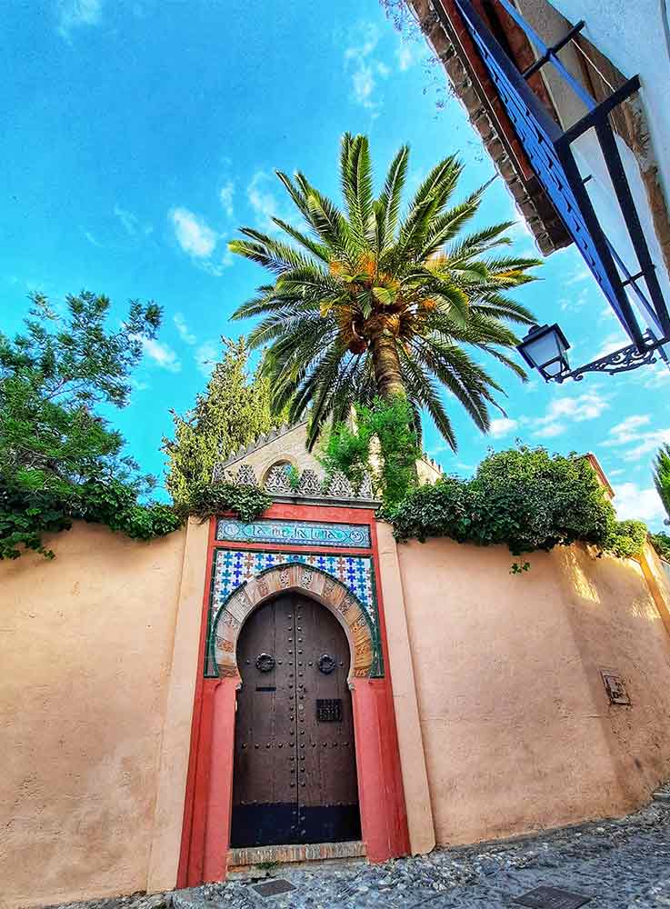 The doorways in the Albaicín District showcase their beauty, with red-painted arch and wooden door that captivate the eye.