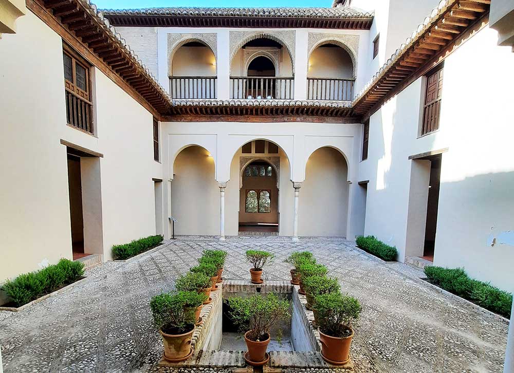 Palacio Dar al-Horra - a palace located in the Albaicin District featuring a cream-white walls with unique roof, archways and potted plants at the courtyard