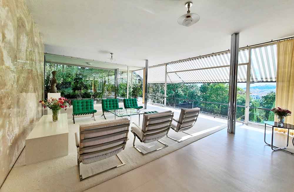 Inside Villa Tugendhat with an open plan room with green chairs and a white rug. 
