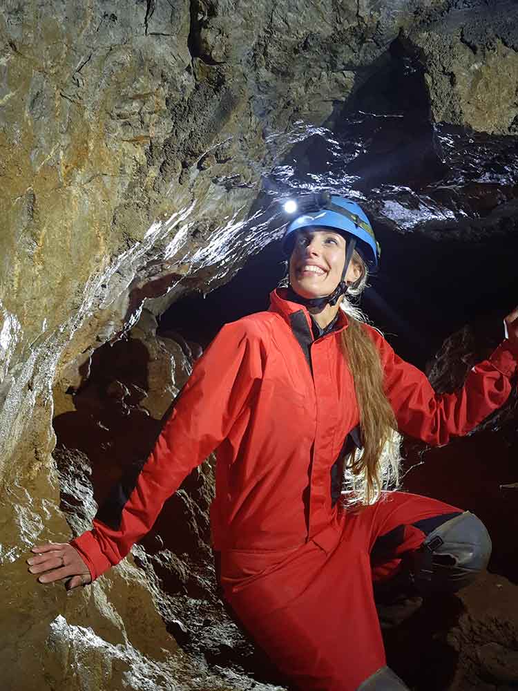 Me Inside the moravian Karst  wearing a red overall and with a blue helmet with a torch on the front.