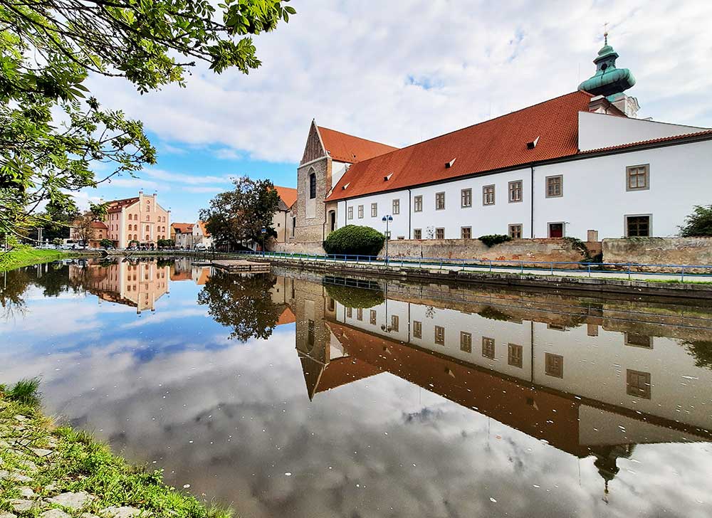 the river in Ceske Budejovice Old Town with old buildings reflected in it. 