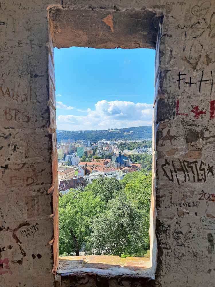 Looking through a window in a wall in Spilberk Castle out across the city.