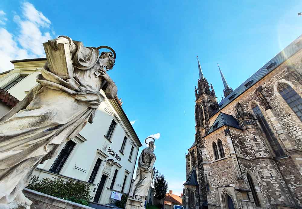 Looking up at the ihe iconic twin spire of St Peter & St Paul Cathedral in Brno with statues of st Peter and St Paul inthe forgeound