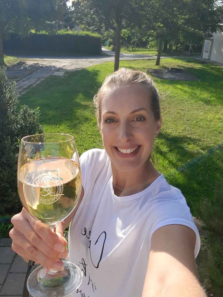 How To Visit 3 Vineyards Near Brno On An Easy Self-Guided Wine Tour, Czech Republic 15 A woman (me) holding a glass of white wine at Zidek winery.